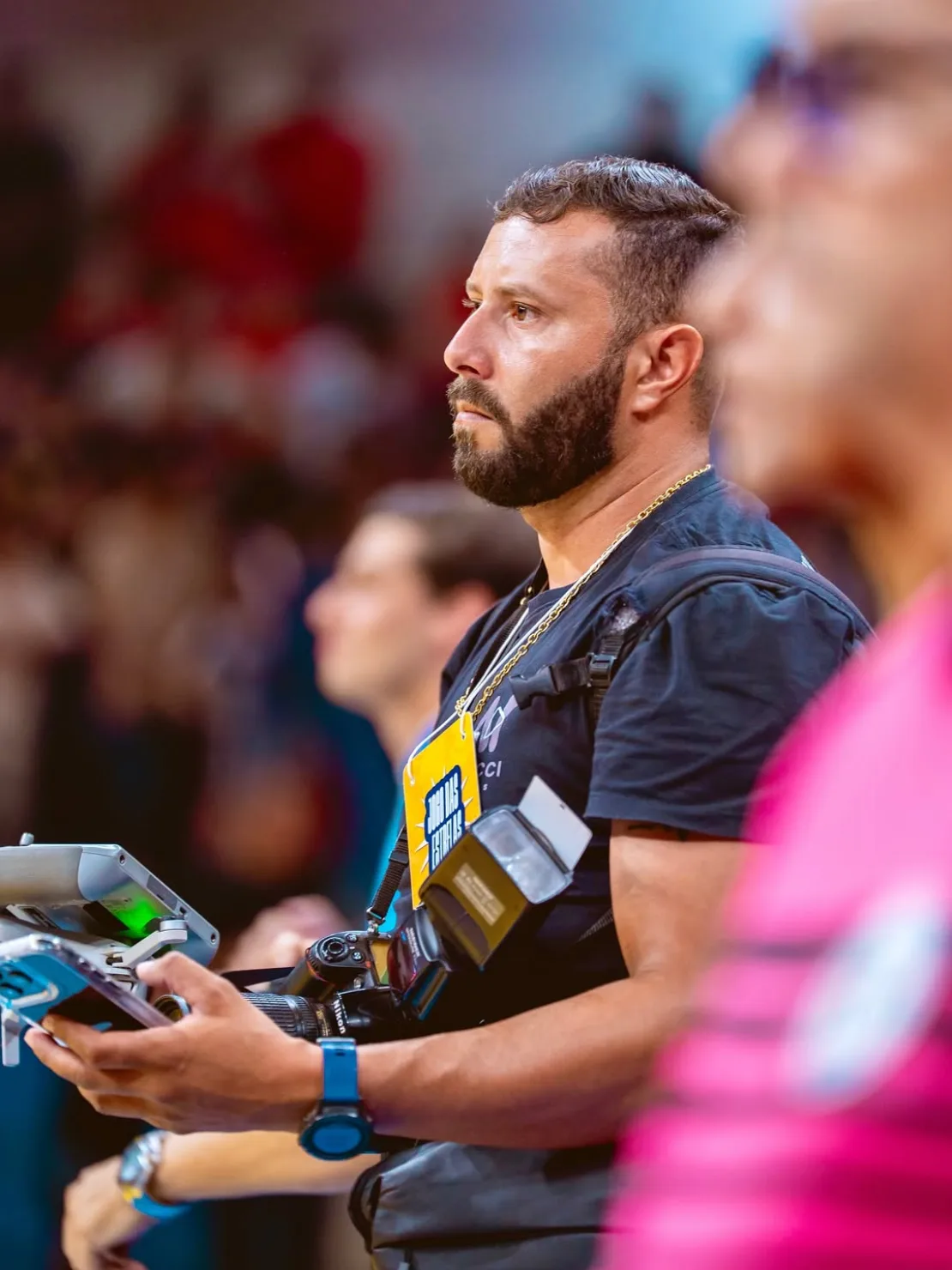 Fotógrafo trabalhando na beira da quadra, com câmeras e equipamento nas mãos