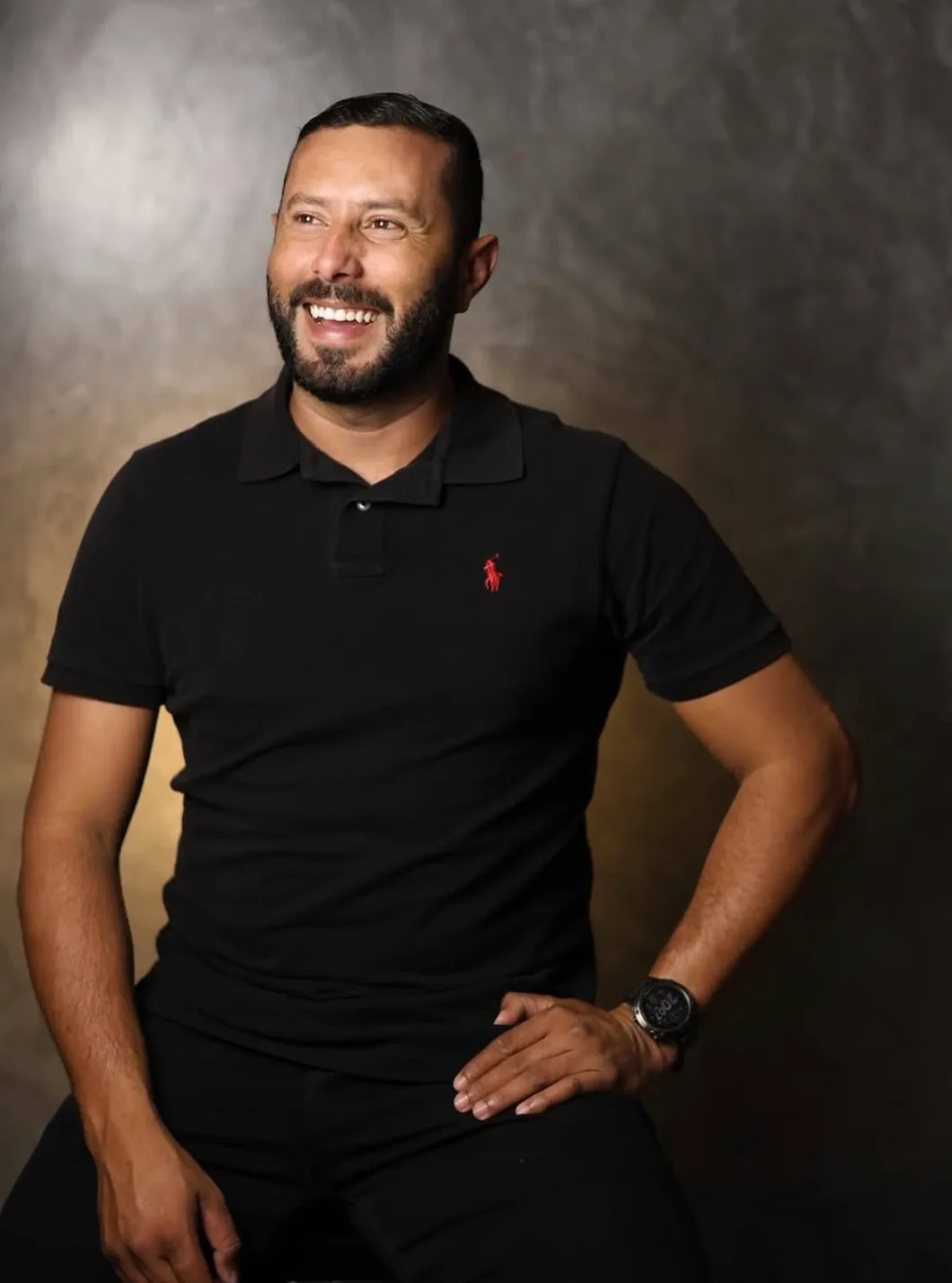 Fotógrafo rindo, sentado, em retrato de estúdio de fundo cinza